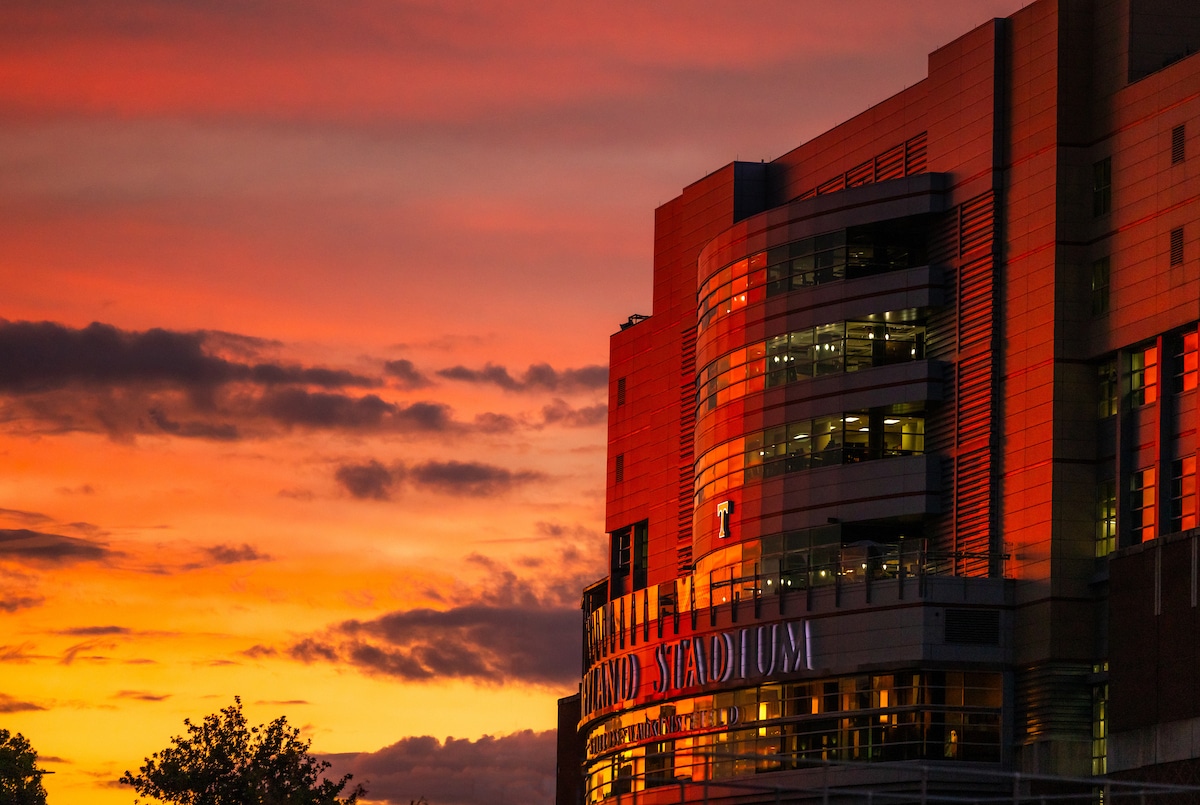 image of the outside of Neyland Stadium at sunset with splashes of red, pink, orange and yellow in the sky