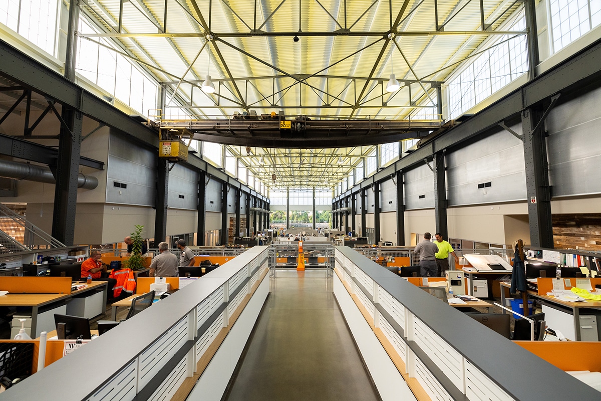 image of the main walkway through the upper level of the Facilities Services Complex with cubicles on either side and showcasing original architecture combined with the innovative use of the space today