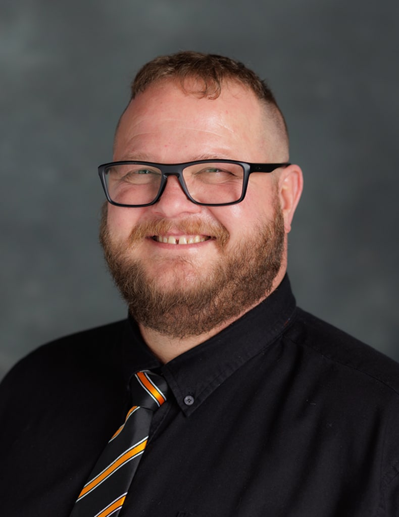 image of Bryan Lord, Director of In-House Construction wearing a black shirt and orange and black striped tie