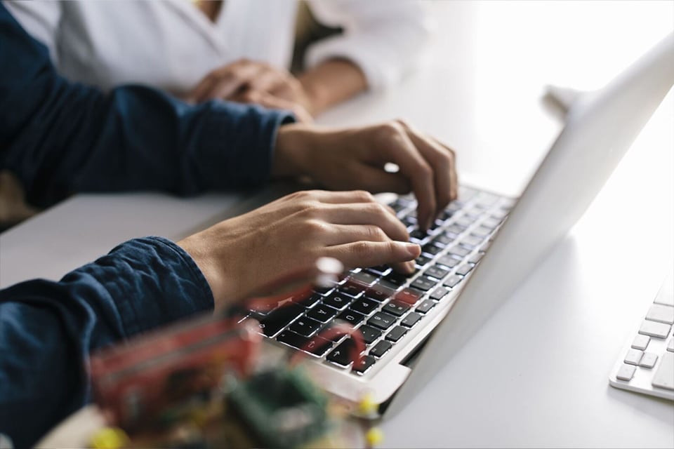 image of a person with their hands typing on a keyboard of a laptop computer