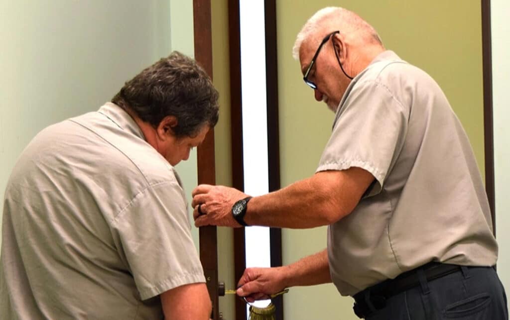 image of Facilities Services team members working on a lock in an interior door on campus