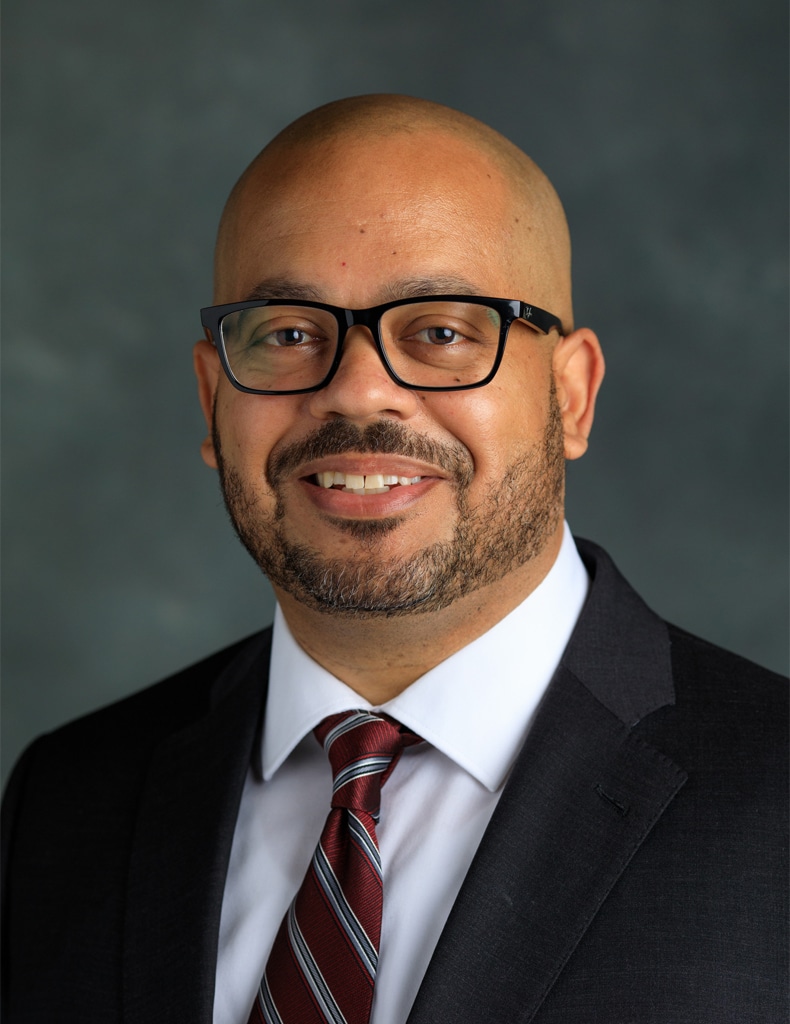 image of Director of Administrative Services Michael Howze wearing a white shirt with a red striped tie and a dark suit jacket