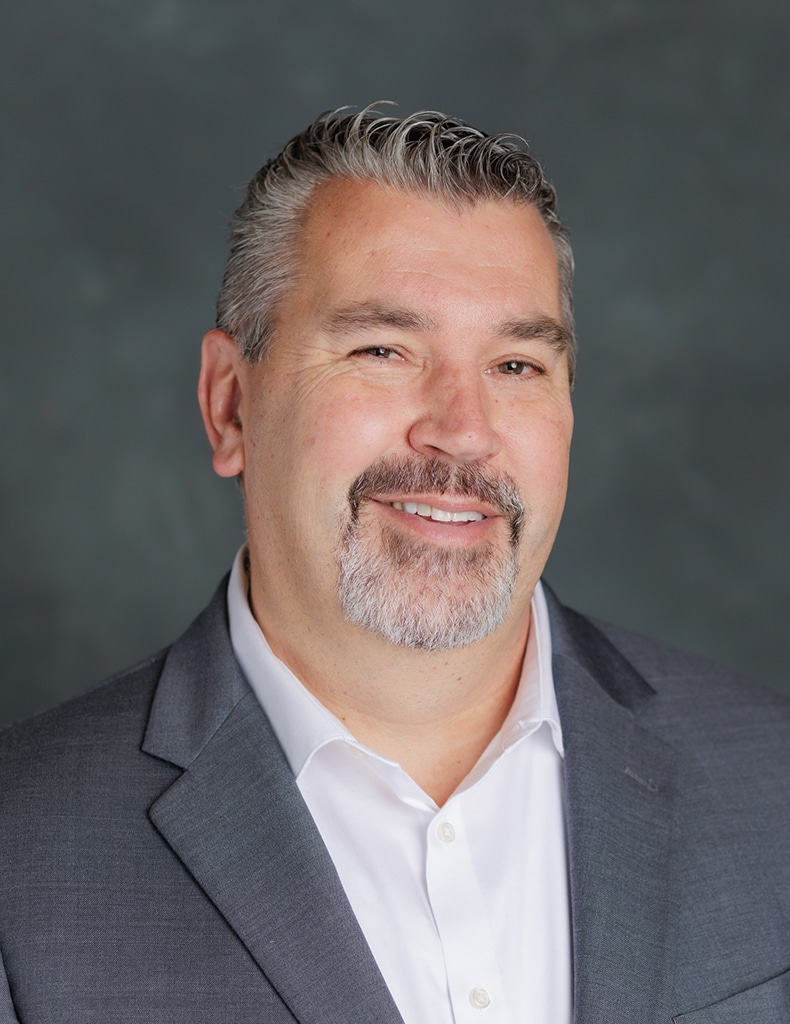 image of Director of Capital Construction, Mike Materna, wearing a white shirt and grey suit jacket