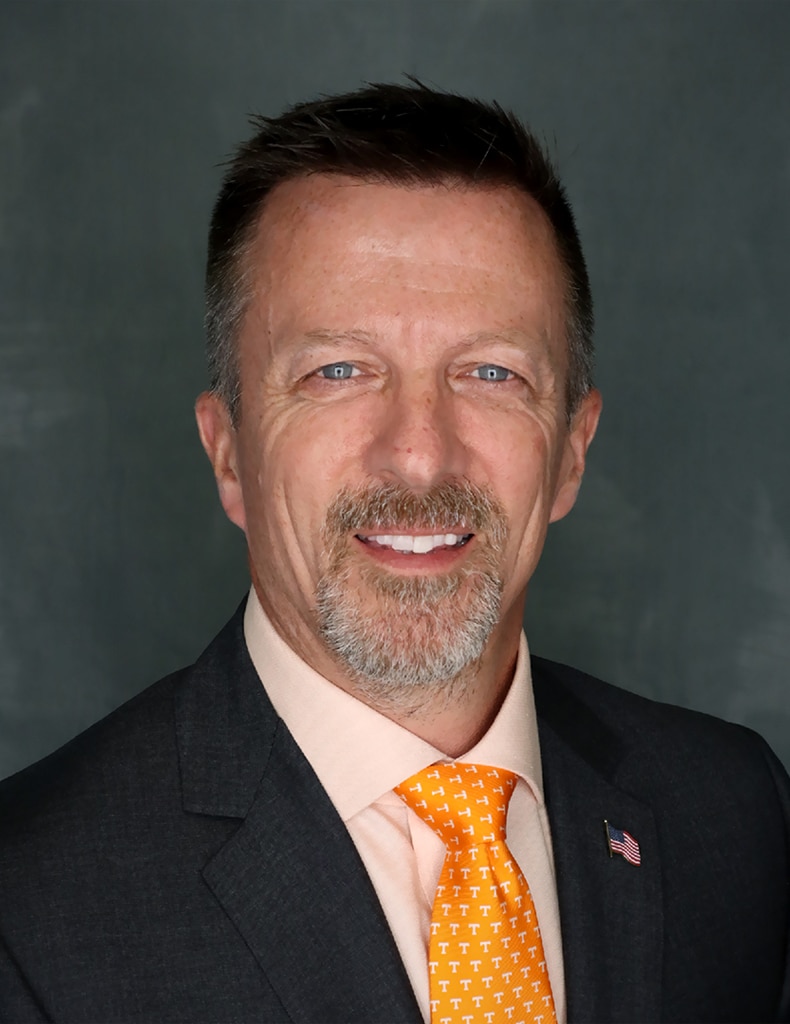 Headshot of Associate Vice Chancellor for Facilities Services, Mike Brady wearing an orange Power T tie, American flag pin, and dark suit jacket