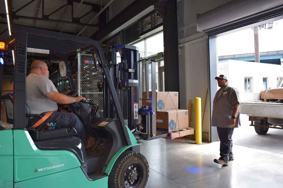 image of two Central Supply staff members preparing to unload a delivery using a forklift