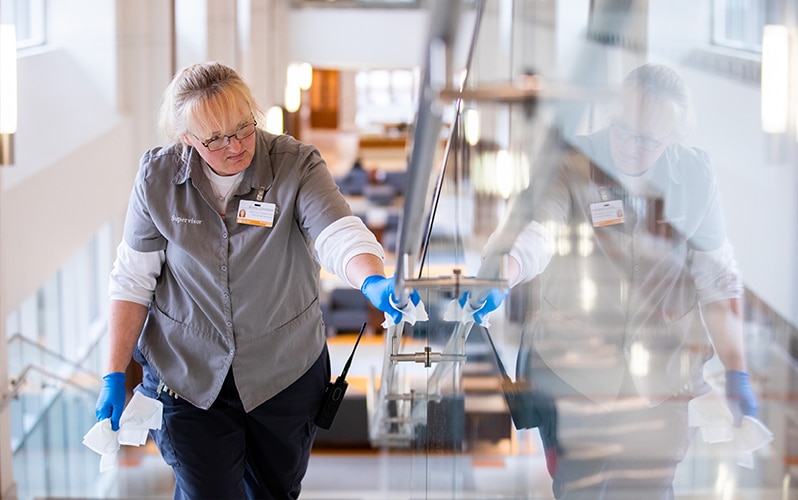image of a Building Services employee disinfecting hand rails on the monumental staircase at the Student Union