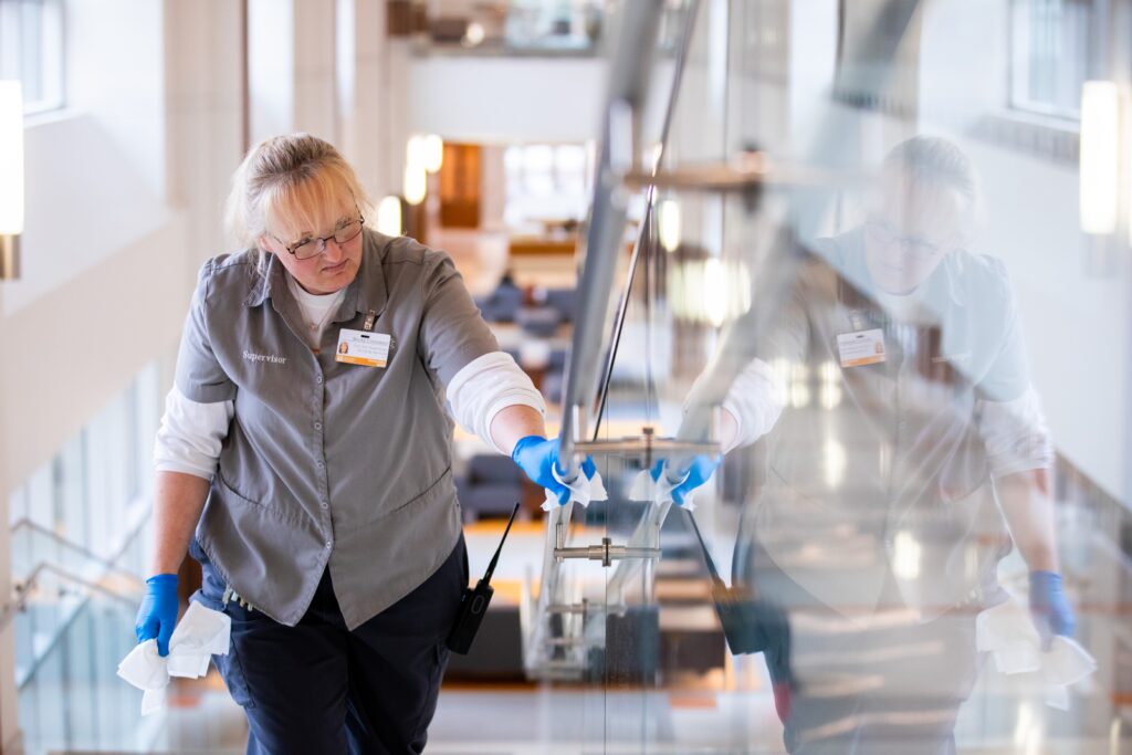 Building Services Supervisor Rebecca Cinnamon disinfects hand rails on monumental stairs in Phase 1 of the Student Union