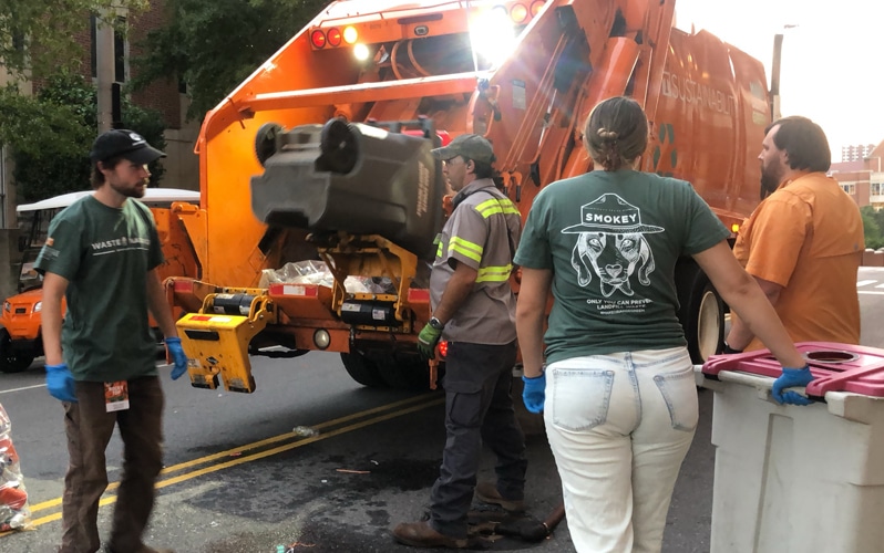 image of Recycling and Sustainability volunteers and staff emptying receptacles into a recycling truck during a Tennessee Football home game