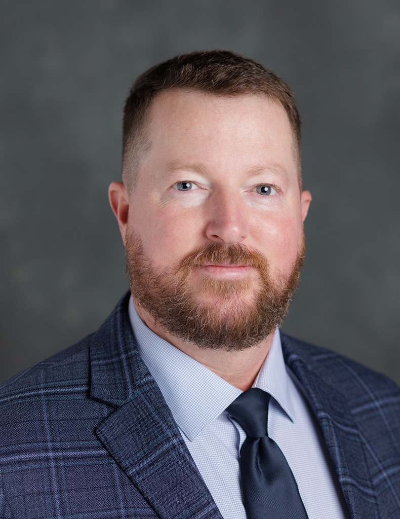 image of Wayne Parsons wearing a light blue shirt, navy tie, and navy plaid jacket