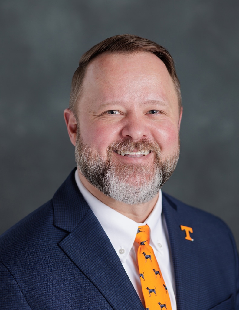 Image of Assistant Vice Chancellor William Maffett wearing an orange tie featuring UT dog mascot Smokey, a Power T pin, and a blue jacket