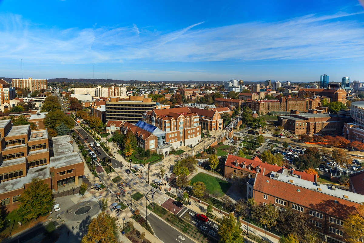 aerial view of campus with blue skies above and campus buildings, pathways, and roadways below