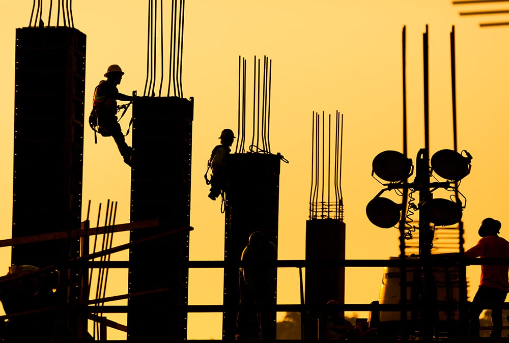 Image of construction workers harnessed in and completing work at a new building site representing management of all construction projects from in-house upgrades to new buildings