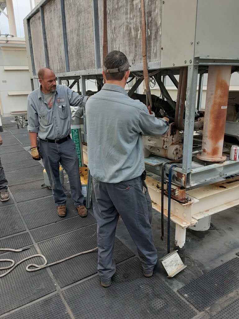 Two Facilities Services team members work on a chiller atop Neyland Stadium