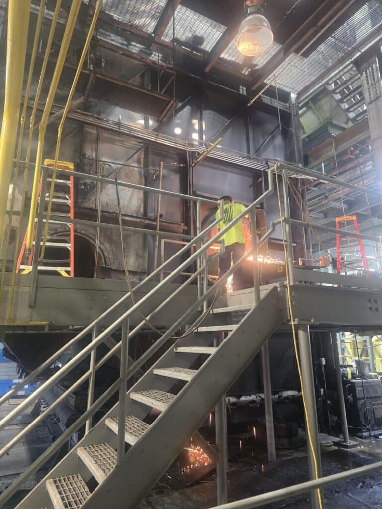 contractors work on disassembling Boiler #1 piece-by-piece at the UT Steam Plant. Image features a man cutting into the metal boiler with proper personal protective equipment in place